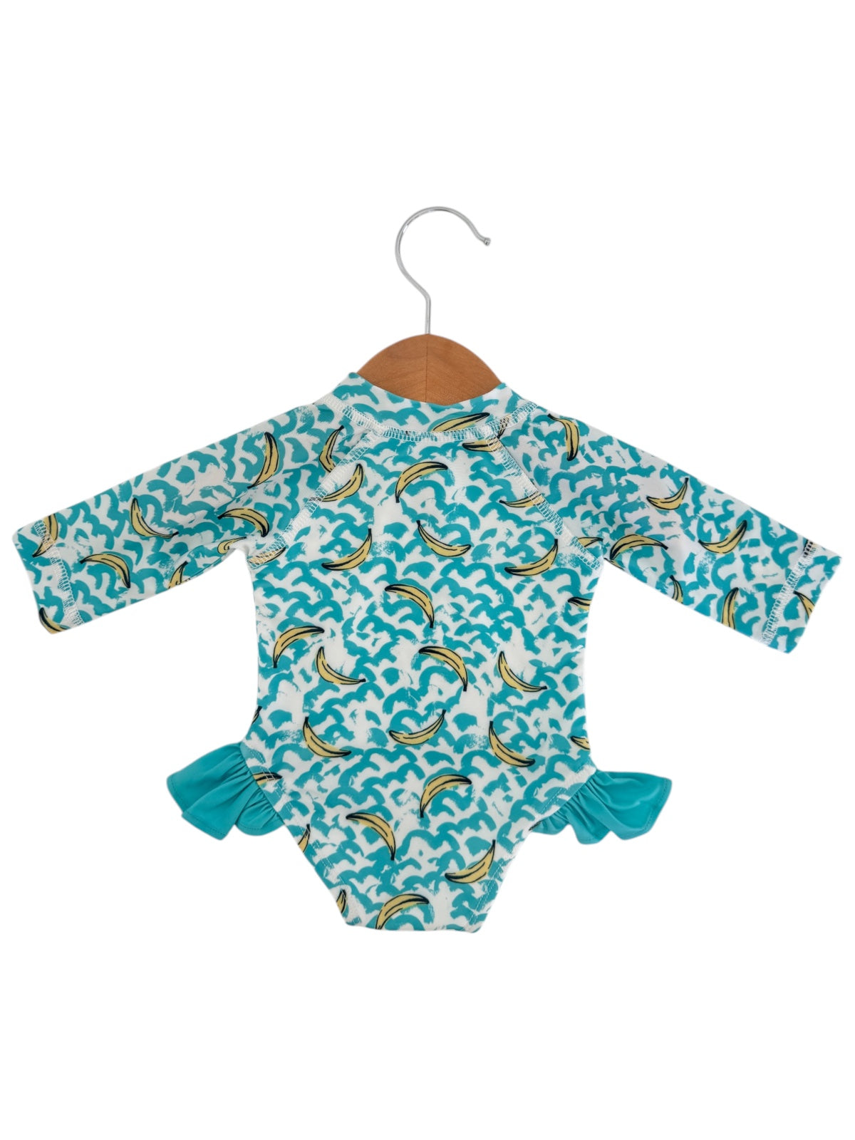 Long-sleeve baby swimsuit with dolphin print, featuring frilly aqua accents, displayed on a wooden hanger.