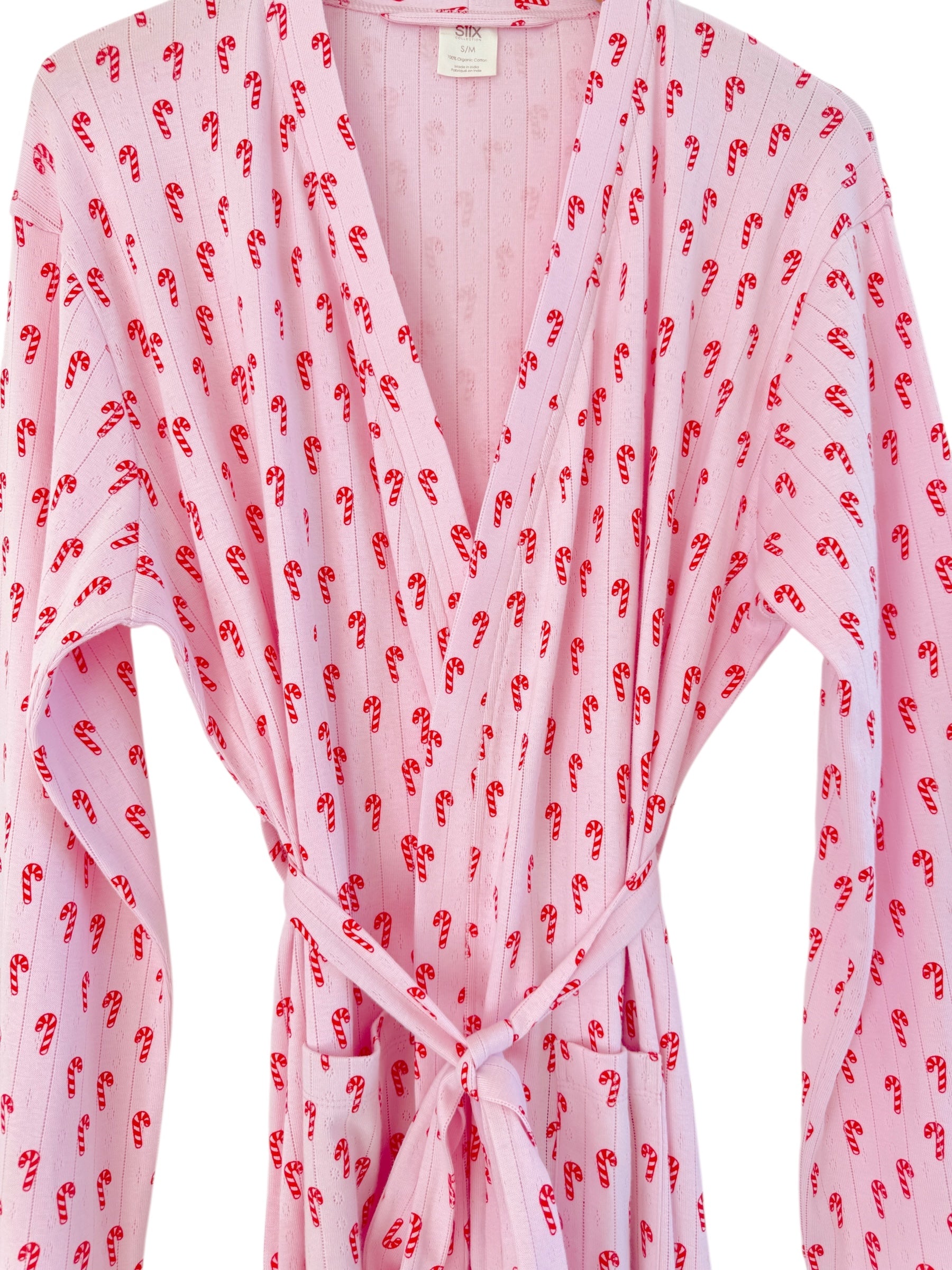 Pink robe with candy cane pattern, featuring a V-neck and tie belt, suitable for holiday lounging.