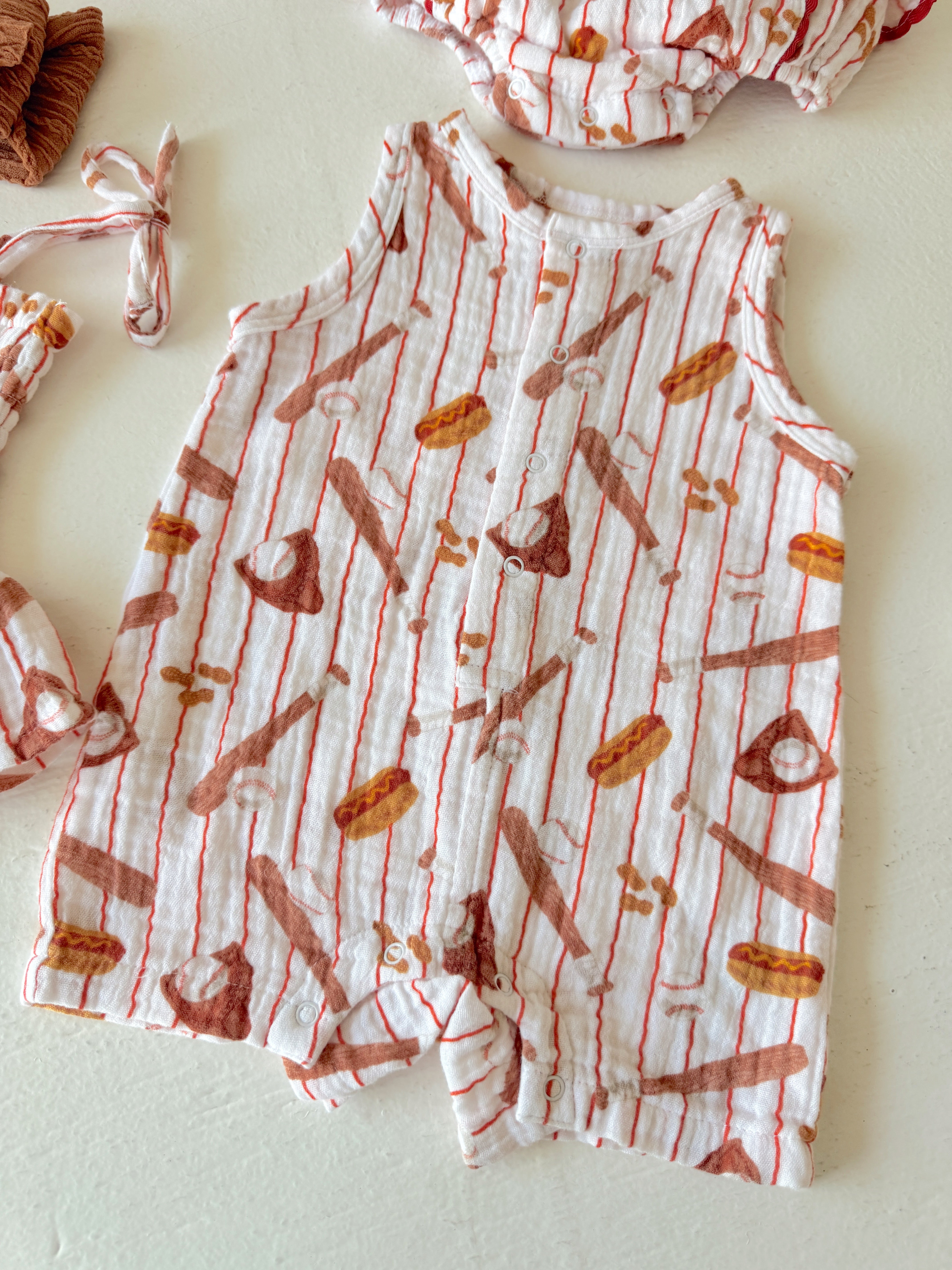 Infant clothing set featuring a playful food-themed print on a sleeveless romper and matching accessories.