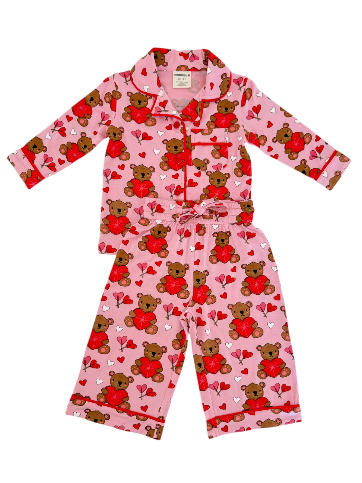 Pink pajama set featuring teddy bears and hearts, perfect for children, with long sleeves and elastic waistband.