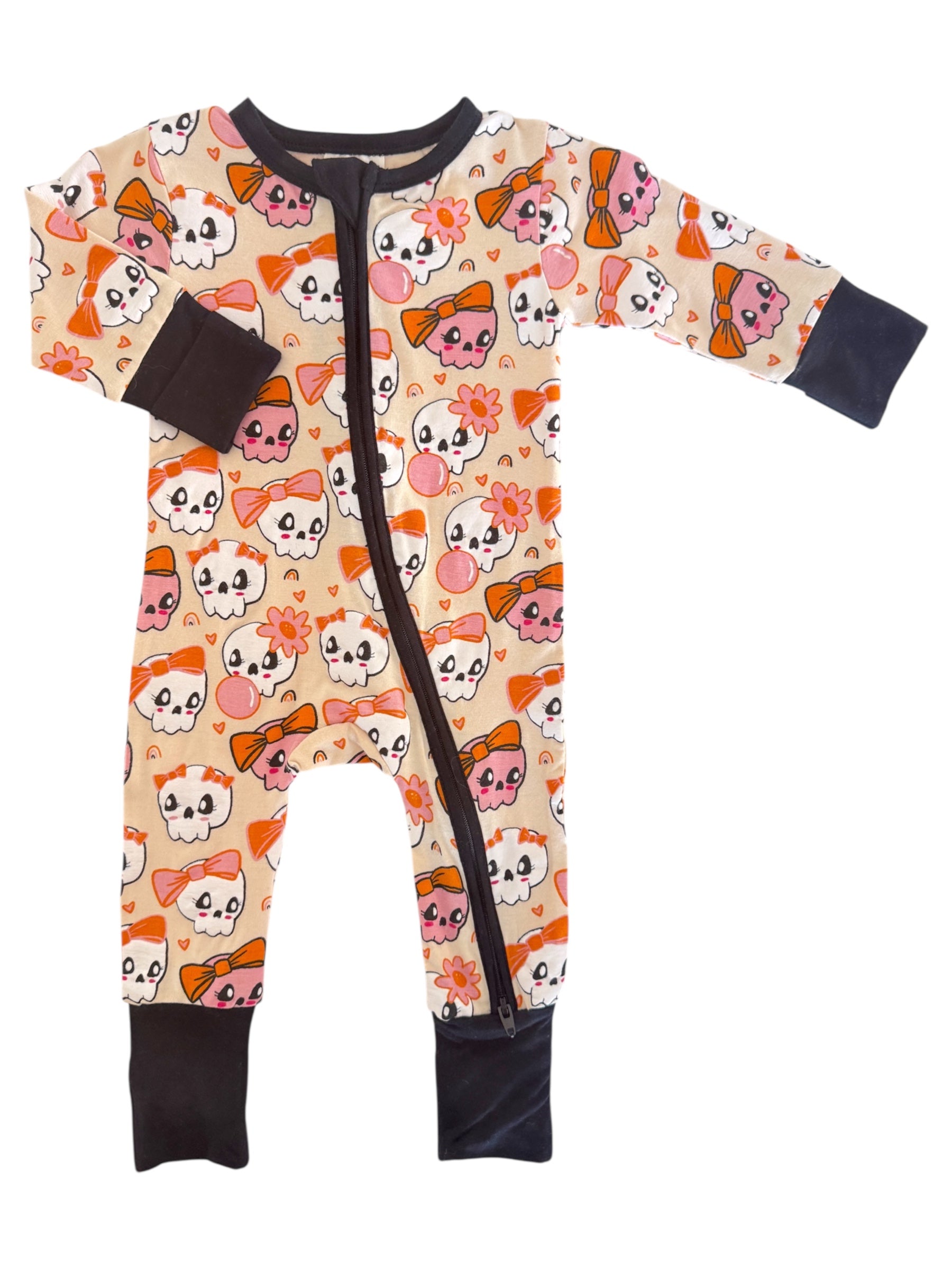 Child's one-piece pajama featuring colorful skull and bow patterns on a light background.