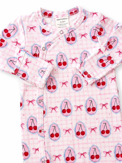 Infant onesie with pink cherry print, featuring bows and snaps, designed for babies 0-3 months.