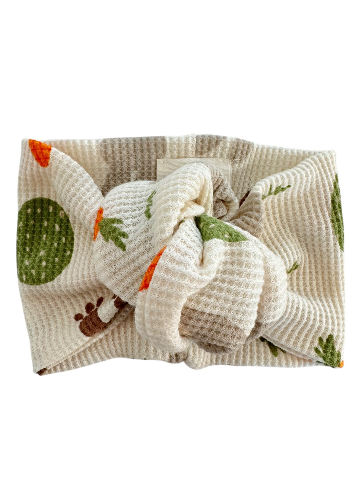Cream fabric headband with carrot and leafy green patterns, knotted design, ideal for casual or playful wear.