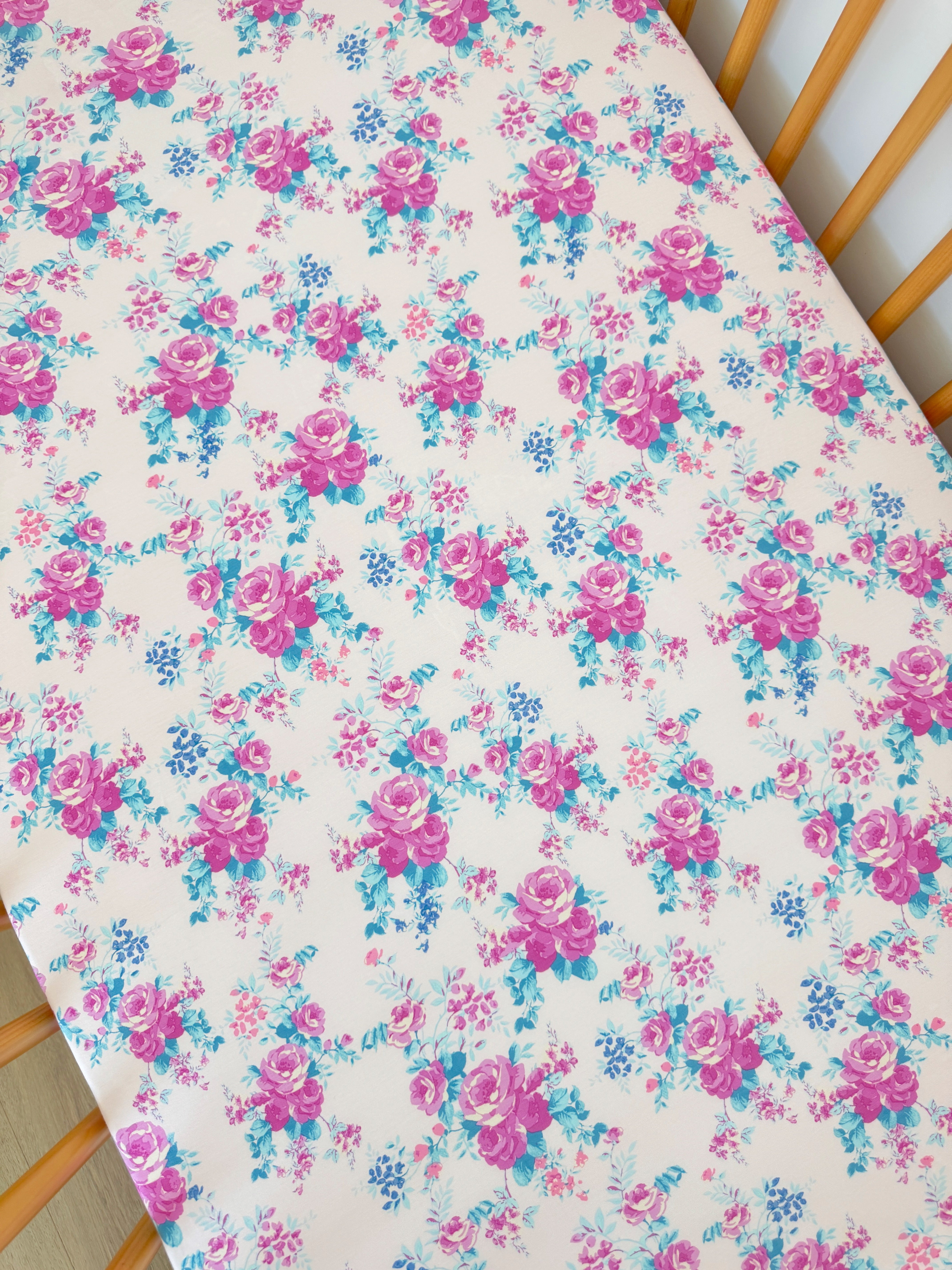 Floral fabric pattern featuring pink roses and blue flowers on a cream background.