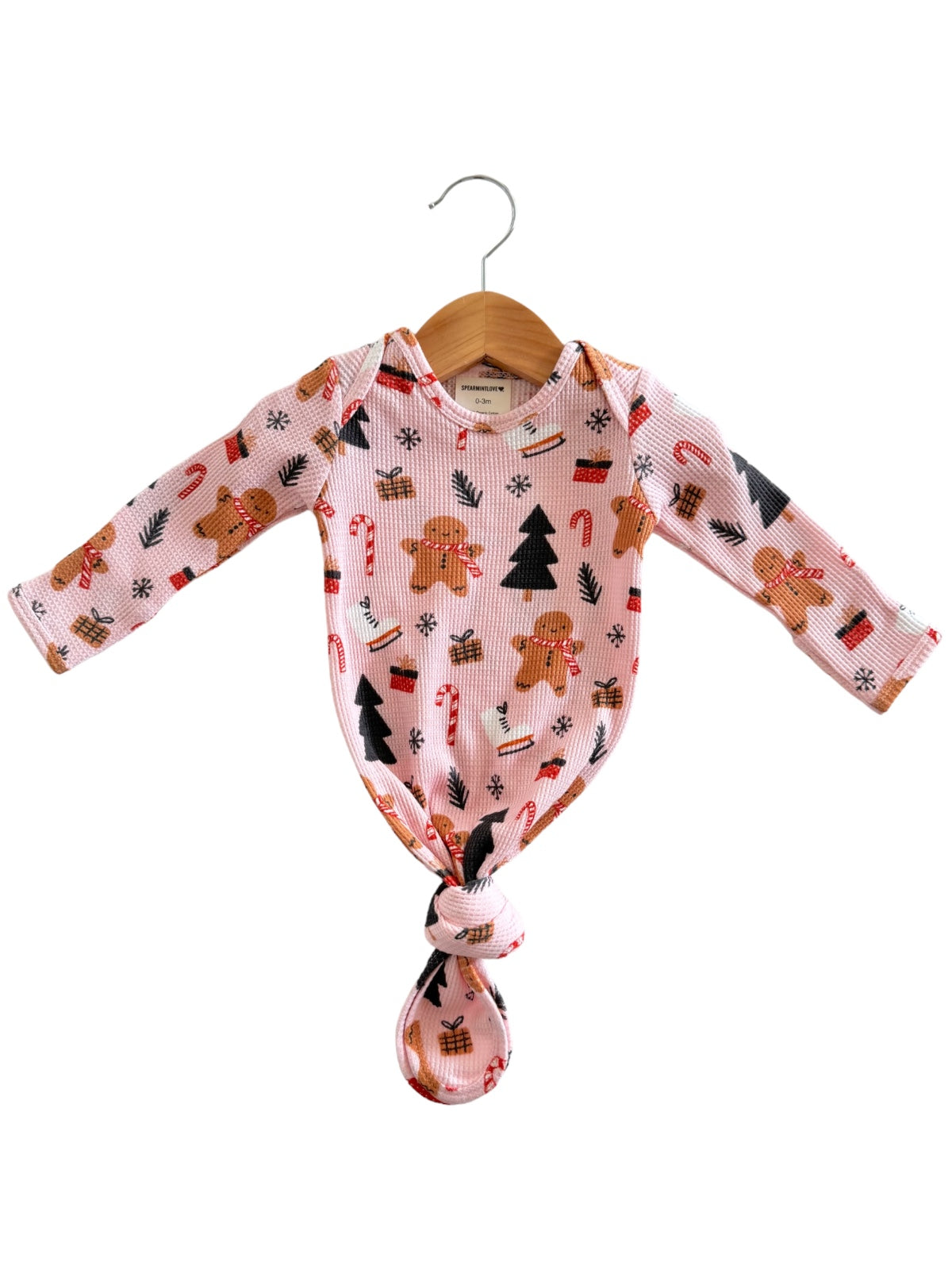 Pink baby onesie with gingerbread, candy canes, and Christmas trees, tied in a knot at the bottom.