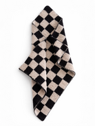 Black and beige checkered towel folded diagonally on a white background.