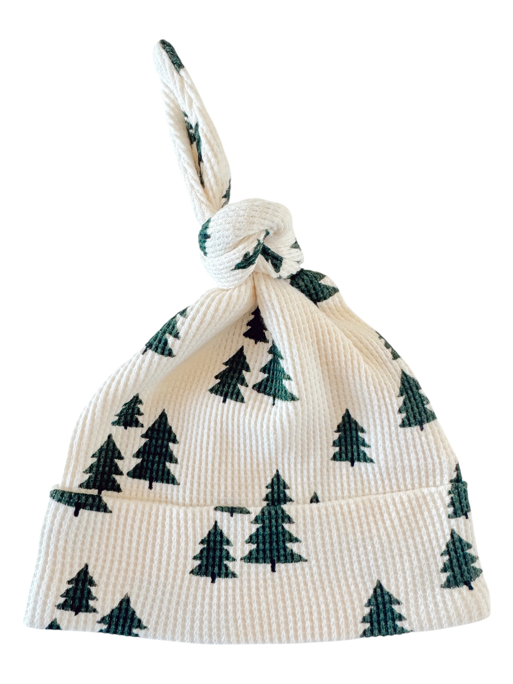 Knotted baby hat with green tree patterns on a white background, ideal for winter outings.