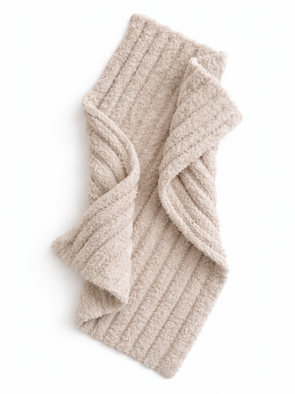 Beige ribbed scarf laid flat, showcasing its soft texture and folded design against a white background.