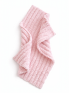 Pink ribbed scarf laid flat on a white background. Soft texture, cozy design suitable for cold weather.