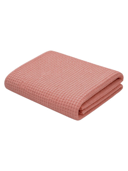 Folded pink waffle blanket with a textured pattern, ideal for cozying up or home decor.