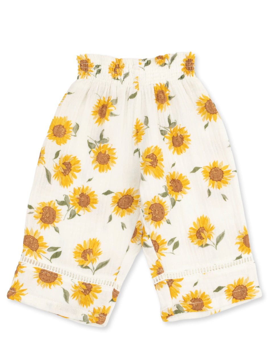 White pants with a sunflower print and elastic waistband, featuring a ruffled hem. Perfect for a cheerful, casual outfit.