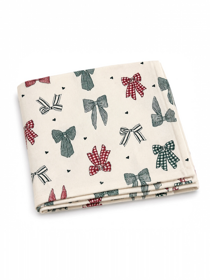 Cream fabric featuring a pattern of colorful bows in red, green, and black on a light background.