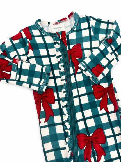 Patterned baby onesie with teal and white checkered fabric and red bows, featuring a zipper and ruffled details.
