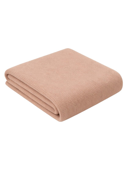 Light pink folded blanket showcasing a textured fabric, ideal for cozy home decor.
