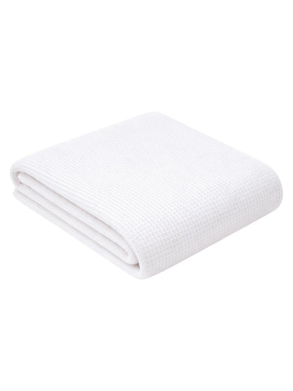 Folded white towel with a textured pattern, placed on a light background.