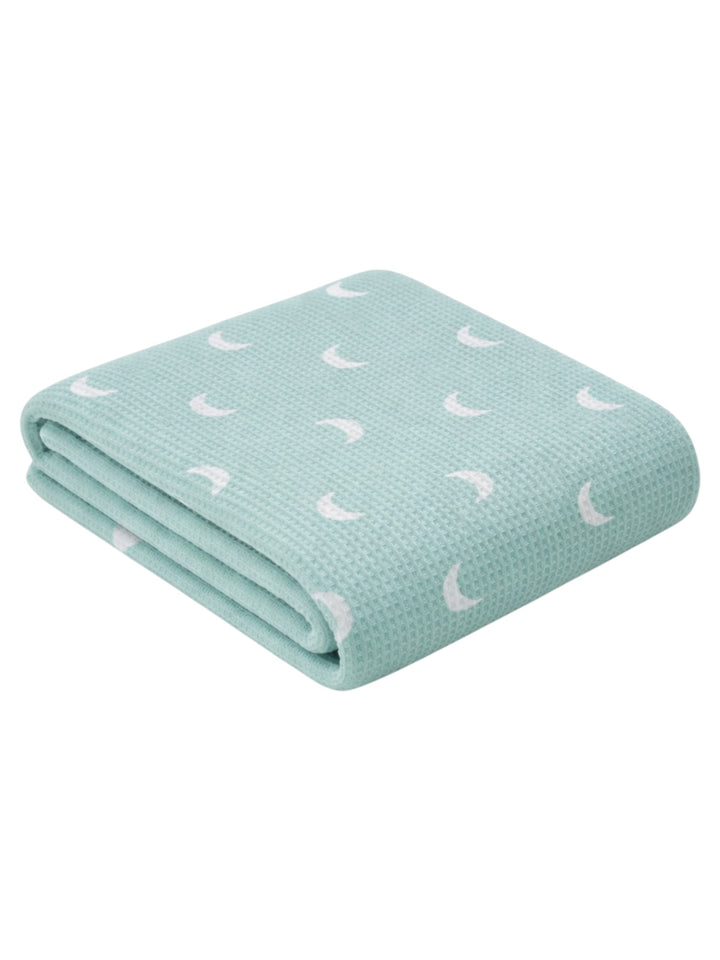 Light green blanket with a textured pattern and white crescent moons, folded neatly on a white background.