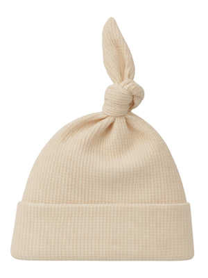 Cream-colored knit hat with a knot at the top and a folded brim. Ideal for newborns or chilly weather.