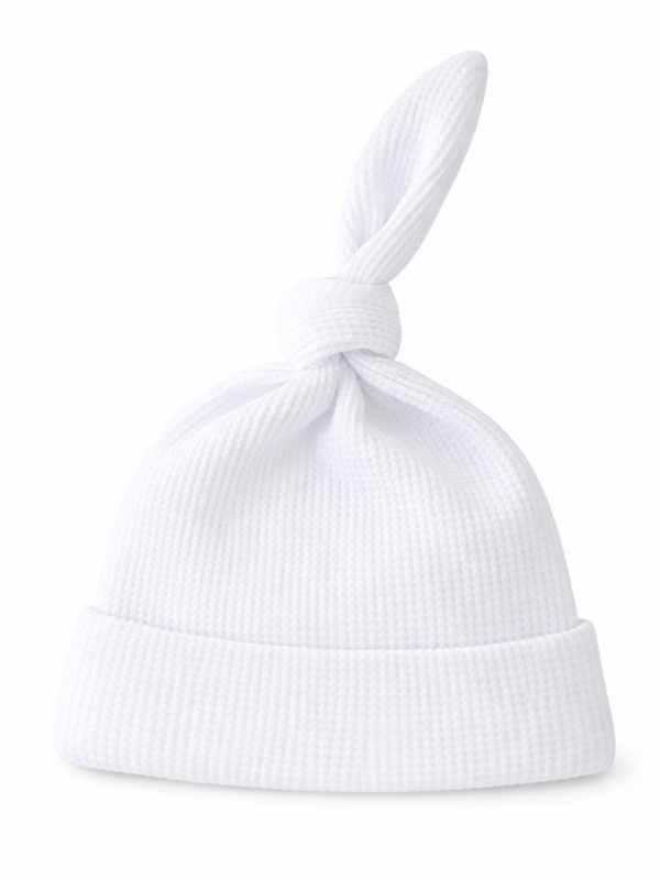 White baby hat with a knot at the top and a folded brim, made from textured fabric.