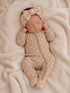 Newborn baby girl sleeping on a cozy blanket, wearing a floral onesie and a matching headband.