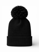 Black knit beanie with a large pom-pom on top, featuring a rolled cuff.