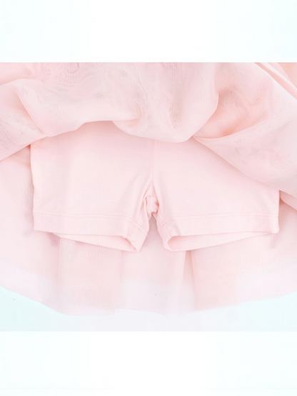 Light pink shorts layered under a soft, sheer tulle fabric. Ideal for dance or casual wear.