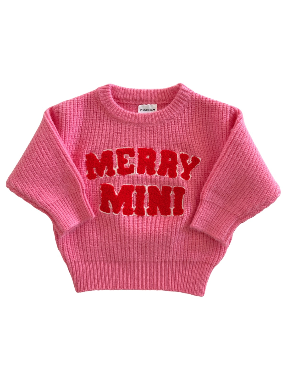 Pink sweater with "MERRY MINI" text, featuring a ribbed texture and wide sleeves. Perfect for festive occasions.