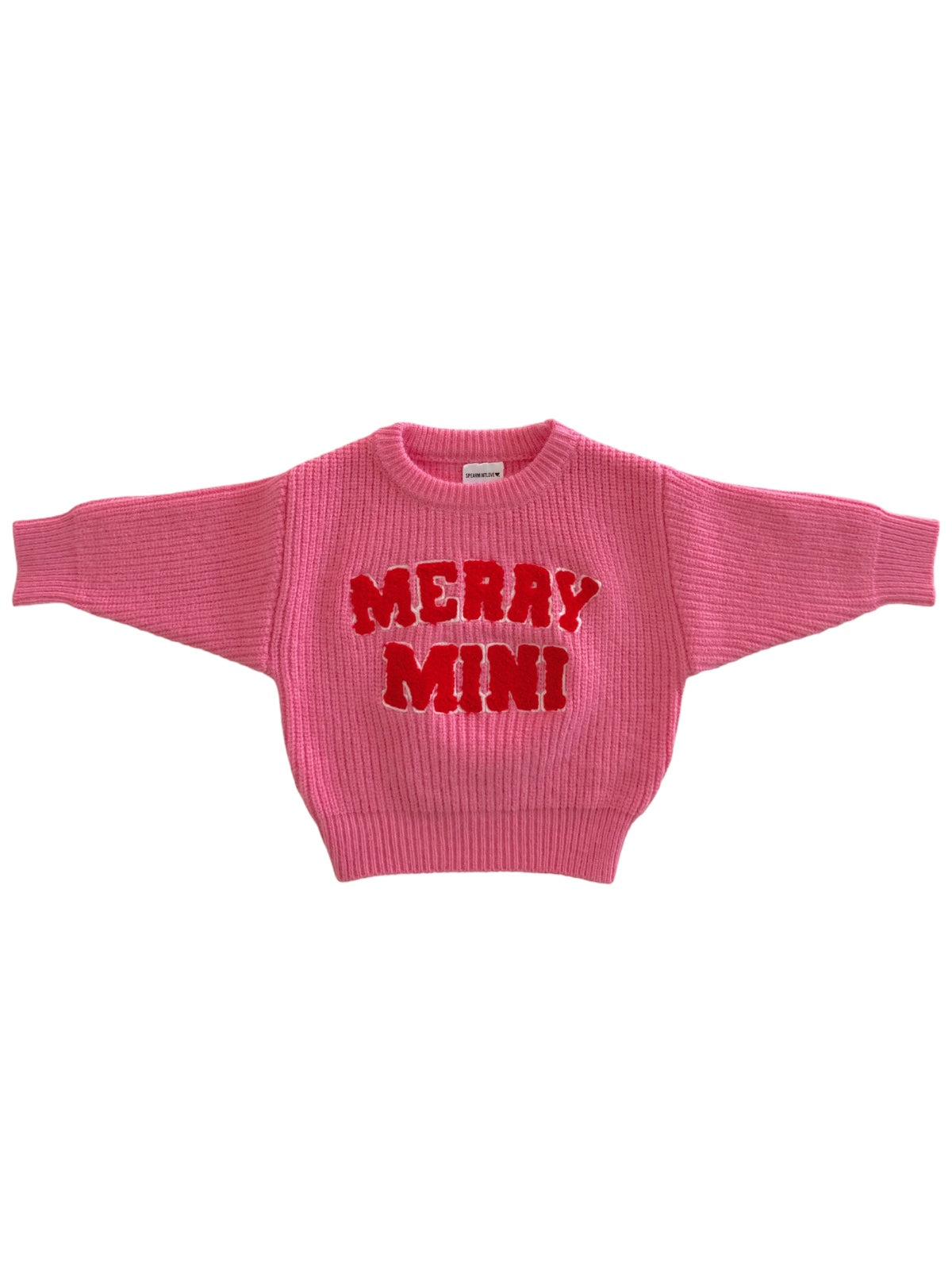 Pink sweater with "MERRY MINI" in bold red letters on the front, featuring a ribbed texture and wide sleeves.