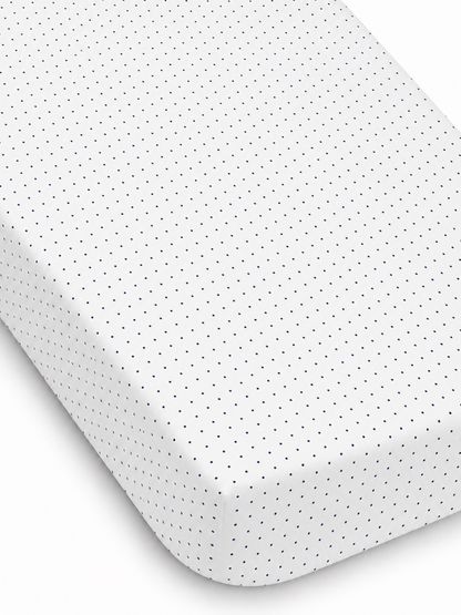 White fitted sheet with navy blue polka dots, showcasing texture and neat edges. Ideal for bedding decor.