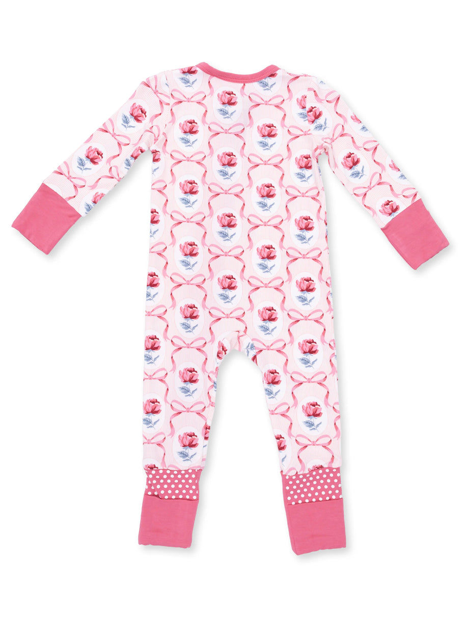 Back view of pink floral-patterned children's pajamas with long sleeves and polka-dot trim.