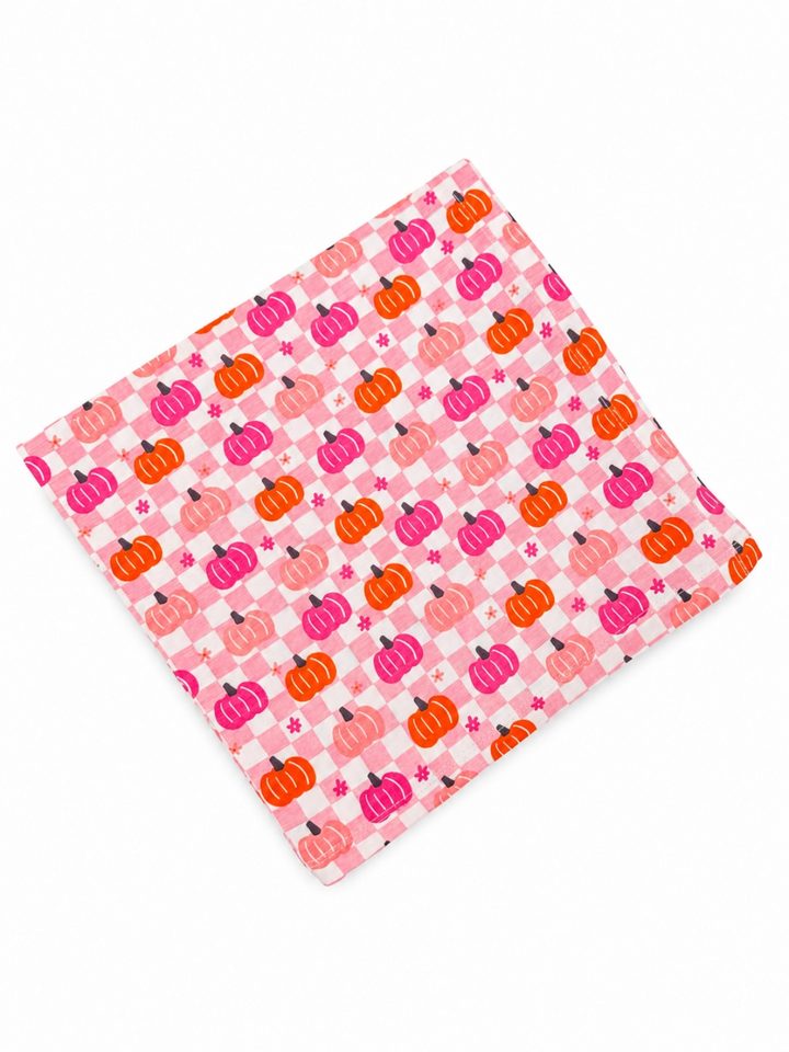 Colorful fabric featuring pink, orange, and purple pumpkins on a checkered background.
