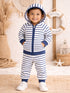 Smiling toddler in a striped hoodie and pants, standing on a beach-themed background, with decor elements nearby.