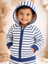 Smiling child in a striped hoodie with a hood, standing in a soft, neutral background.