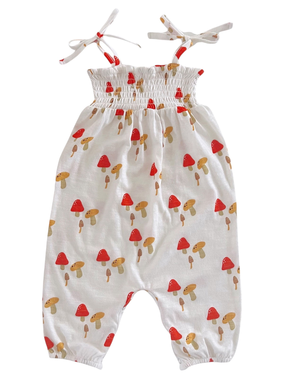 White romper with red and brown mushroom print, featuring thin straps and a smocked bodice design.