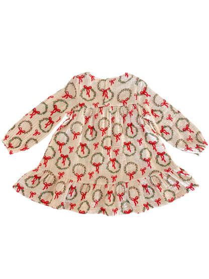 Smocked dress with long sleeves, featuring a festive wreath and ribbon design in red and green on a white background.