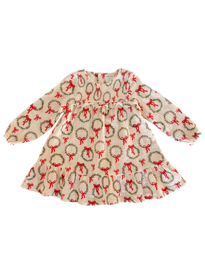 Cream dress with festive wreath and bow pattern, featuring long sleeves and a flared skirt. Perfect for holiday occasions.