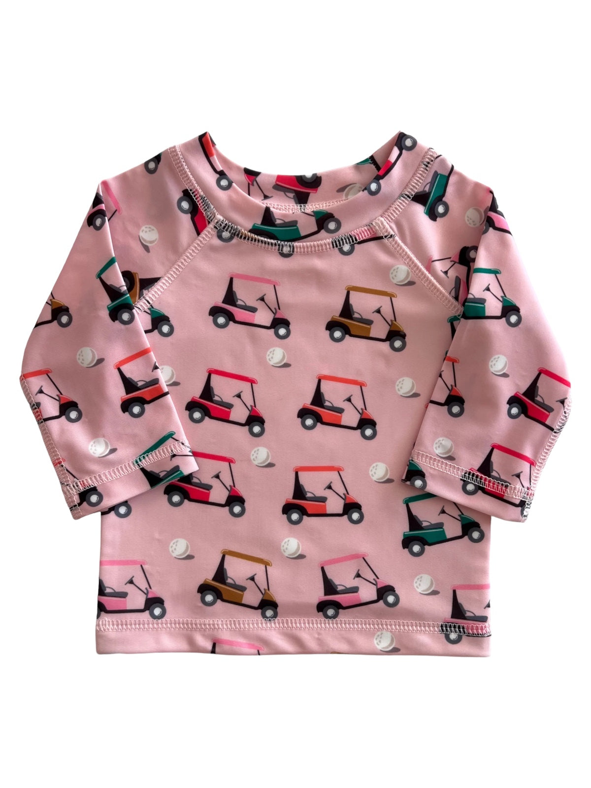 Pink long-sleeve shirt with a playful golf cart pattern and golf balls. Ideal for kids.
