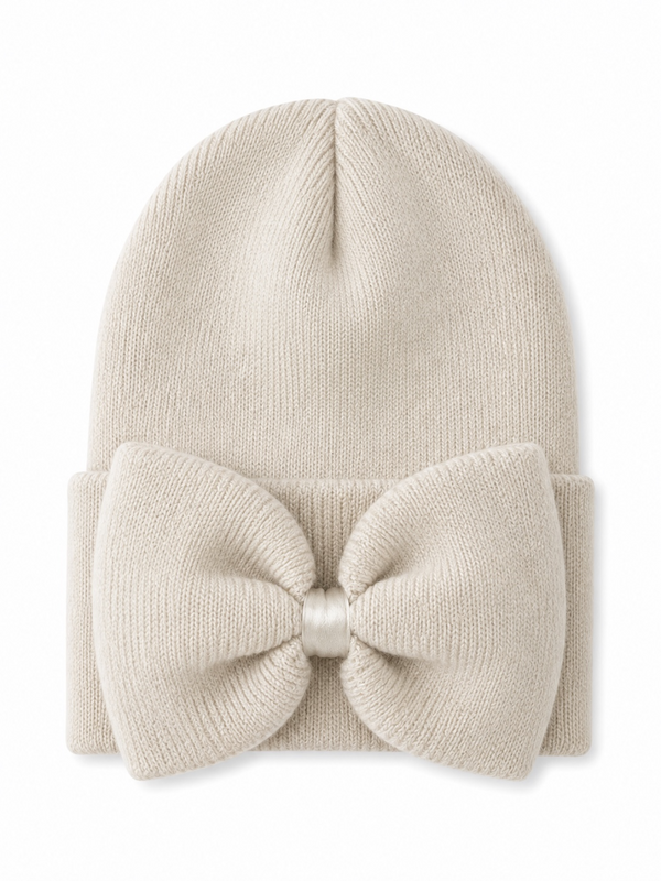 Cream beanie hat with a large bow on the front, perfect for winter fashion.