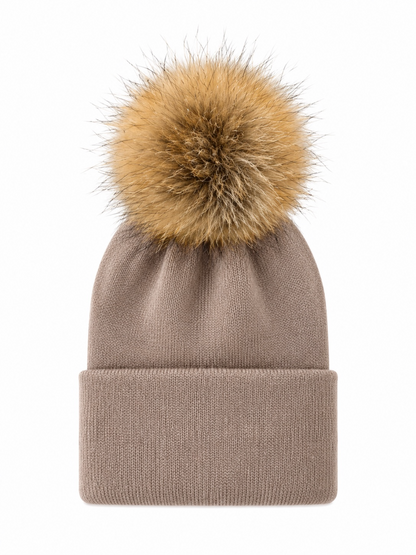 Beige knitted beanie with a fluffy tan pom pom on top, perfect for winter wear.