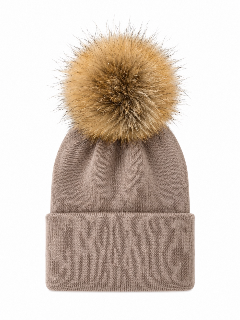 Beige knitted beanie with a fluffy tan pom pom on top, perfect for winter wear.