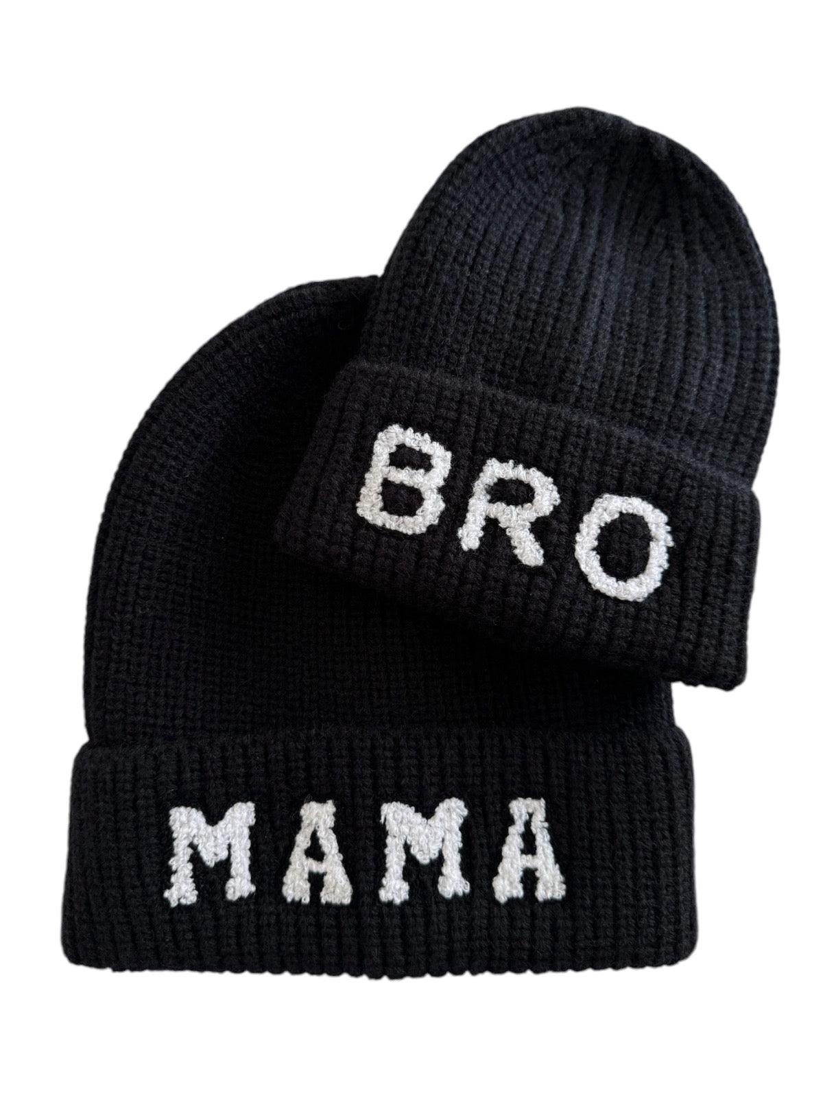 Two black knit beanies, one labeled "MAMA" and the other "BRO" in white lettering.