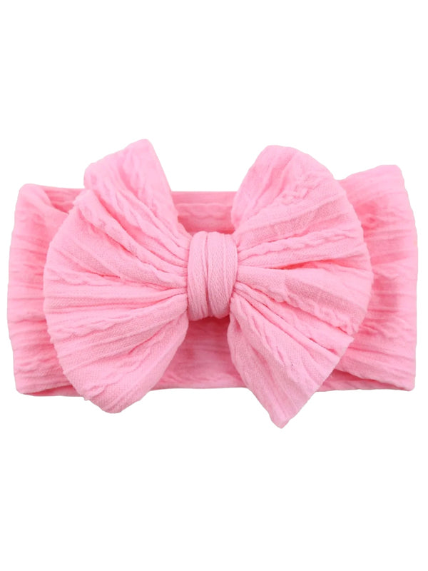 Pink textured headband with a large bow, ideal for children or fashion accessories.