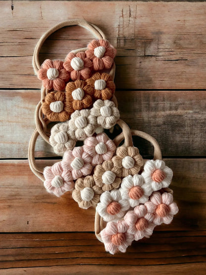 Colorful knitted flower hair ties arranged on a wooden surface.