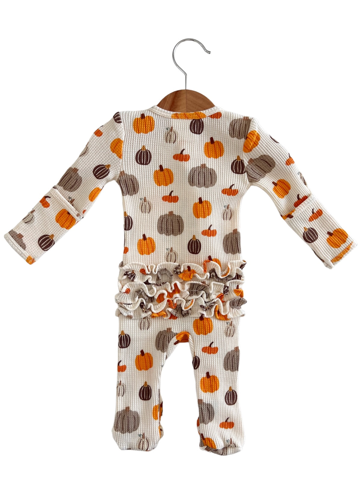 Toddler ribbed romper with colorful pumpkin print and ruffled hem, hanging on a wooden hanger.
