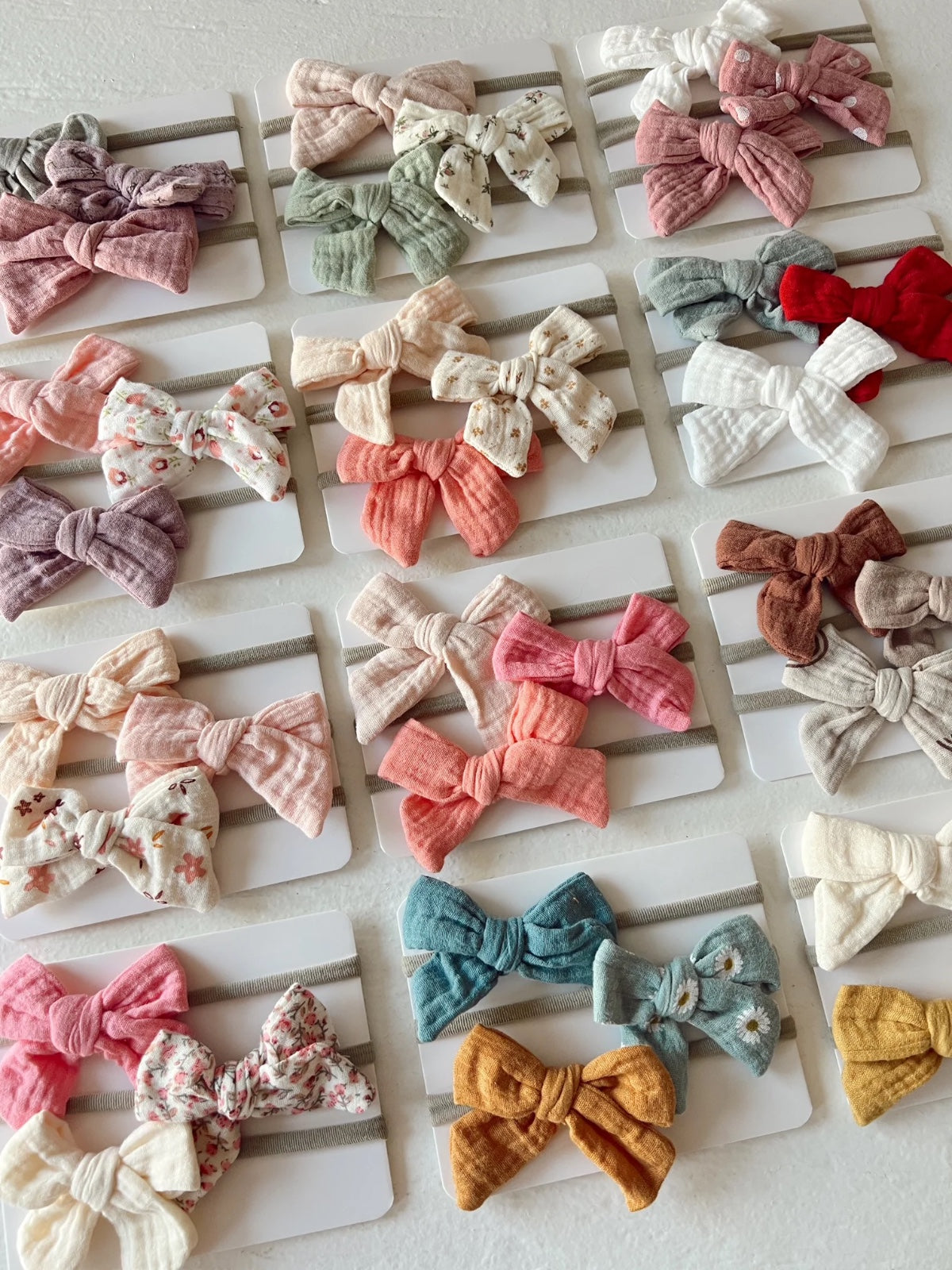 Colorful assorted hair bows displayed on white cards, featuring various styles and patterns.
