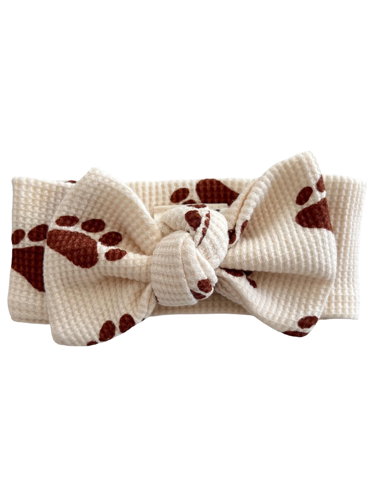 Cream headband with a large bow, featuring brown paw print patterns, ideal for pet lovers.