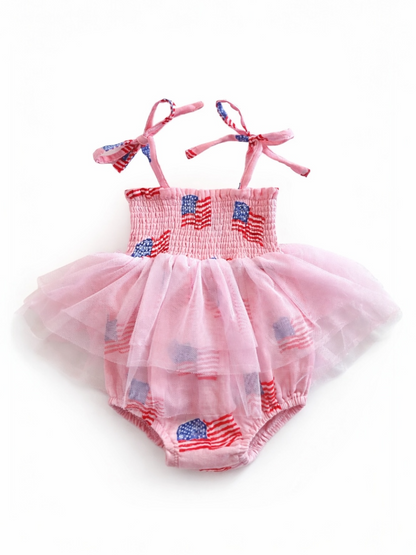 Pink baby romper with American flags and a tulle skirt, featuring shoulder ties. Ideal for festive occasions.
