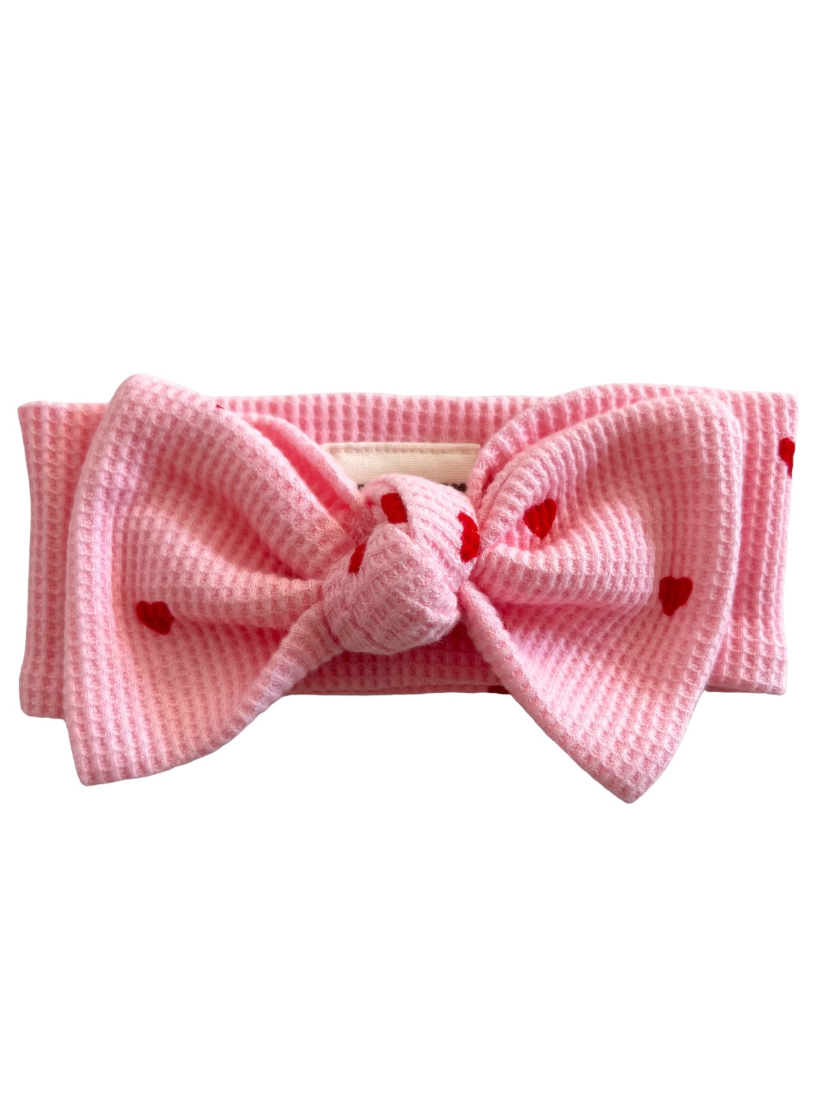 Pink headband with a large bow and red heart patterns, ideal for fashionable looks and everyday wear.