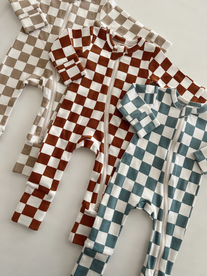 Three checkered baby onesies in brown, blue, and beige laid flat on a light background.