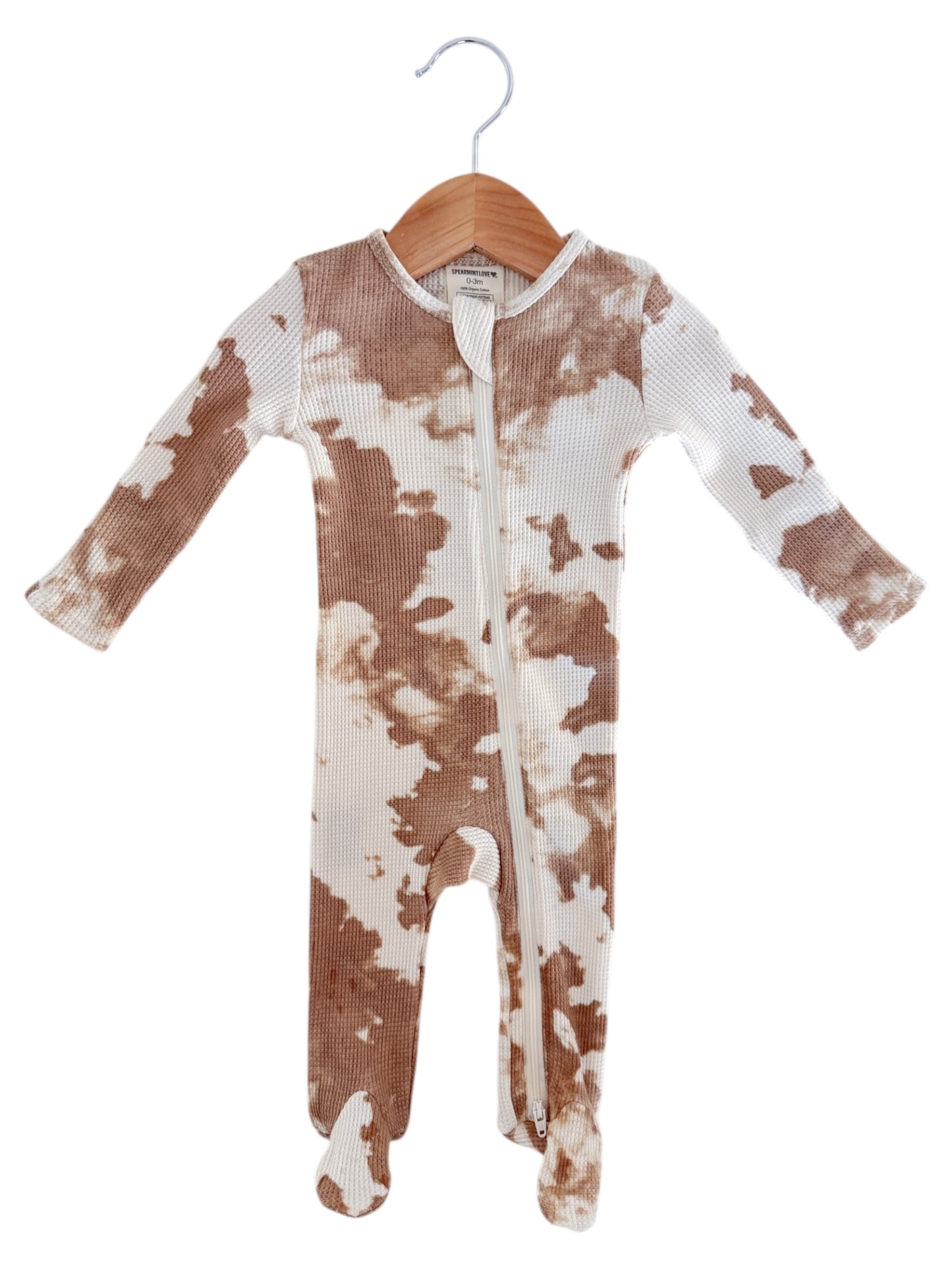 Brown and white patterned baby onesie hanging on a wooden hanger.