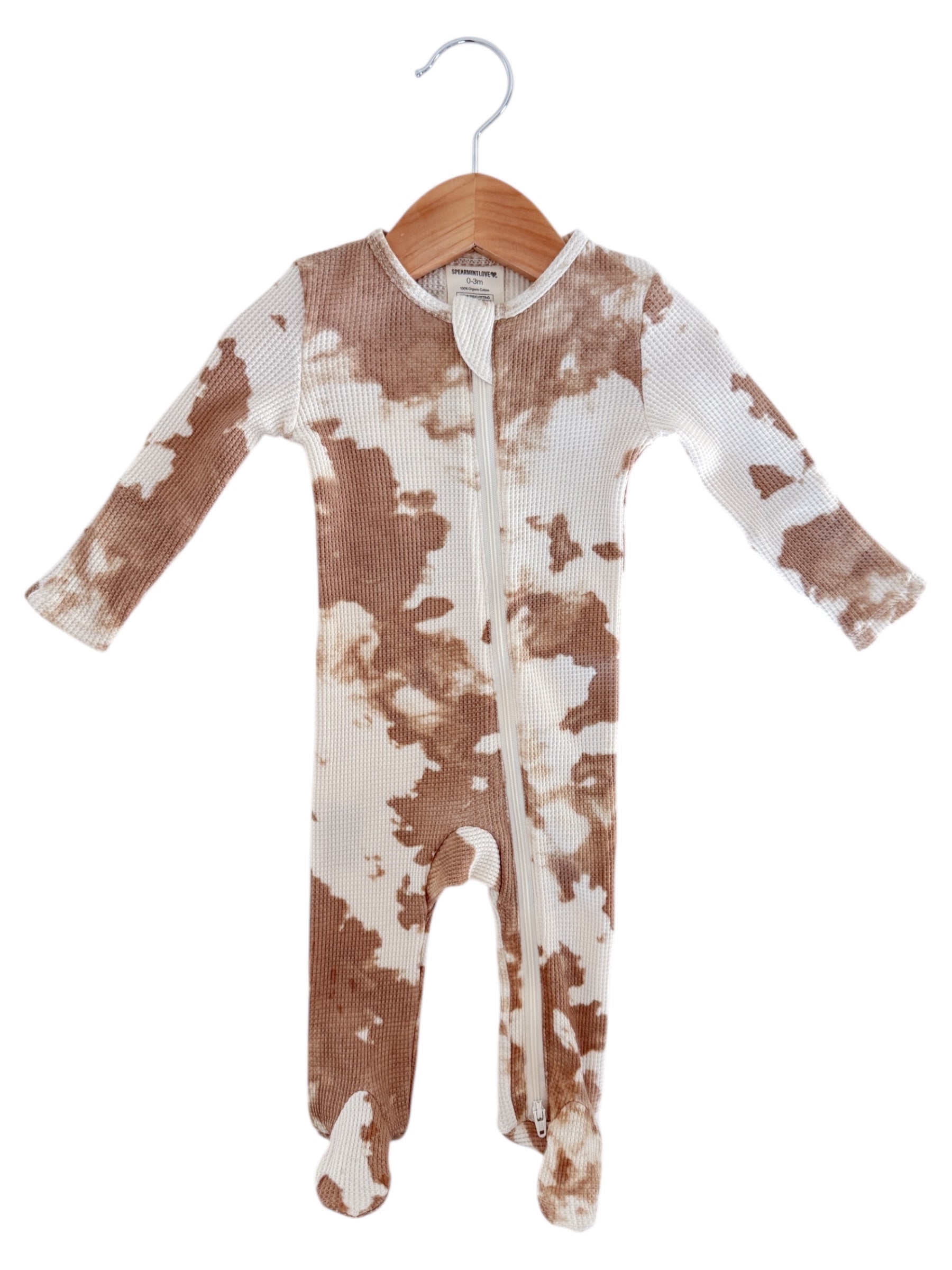 Brown and white patterned baby onesie hanging on a wooden hanger.